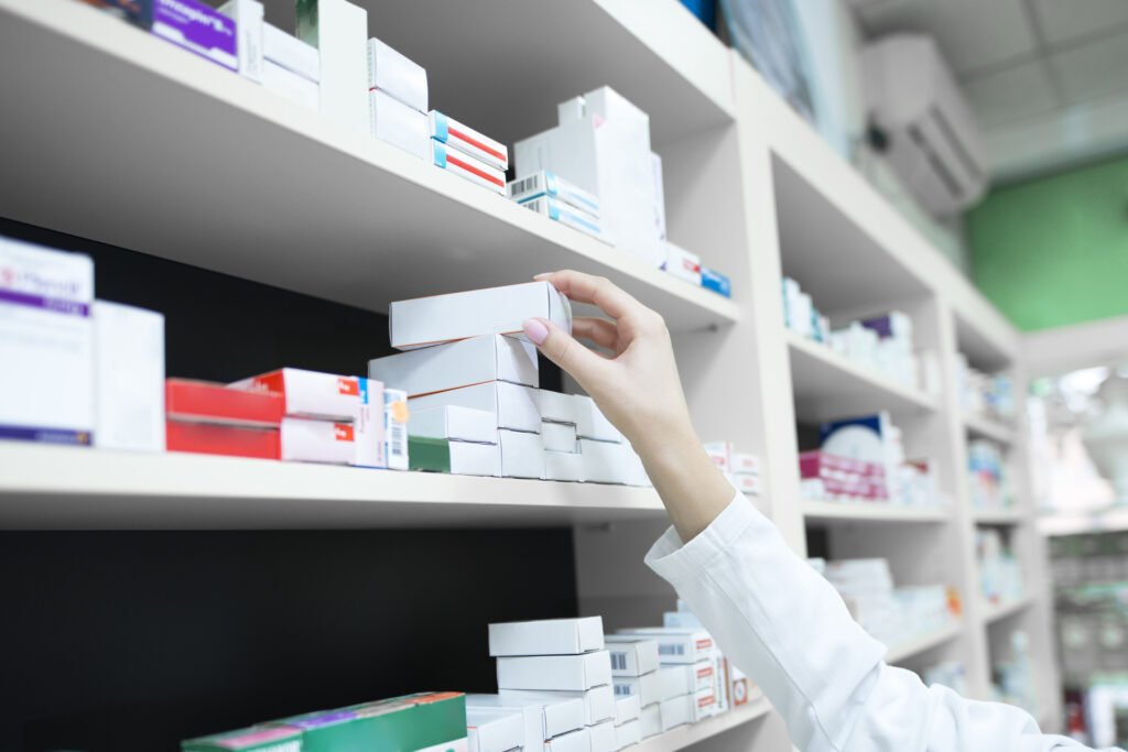 Ristrutturazione della farmacia- vista ravvicinata di un farmacista che prende con la mano una scatola di medicinali dallo scaffale della farmacia